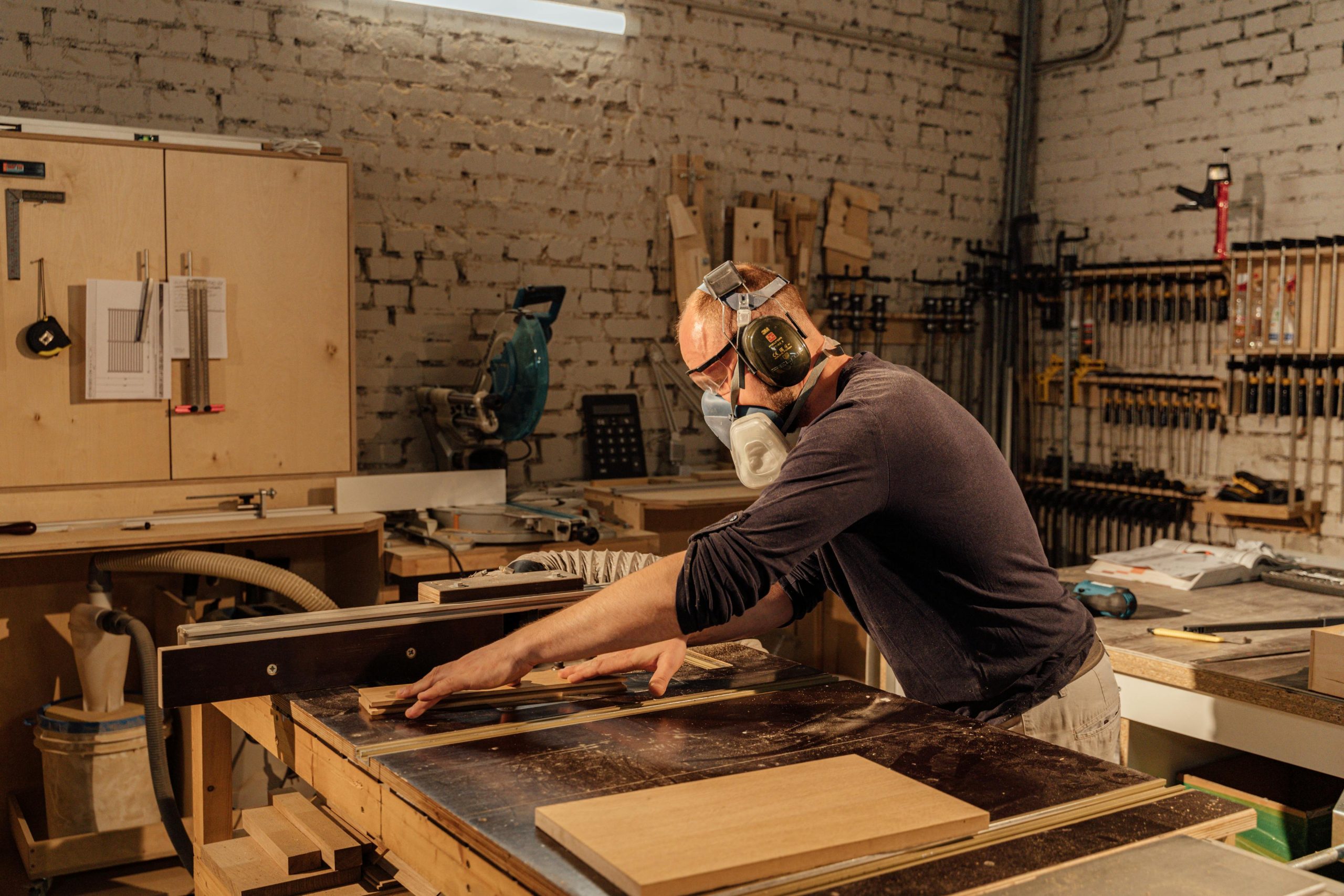 Experienced woodworker using a table saw in a well-equipped woodworking shop.